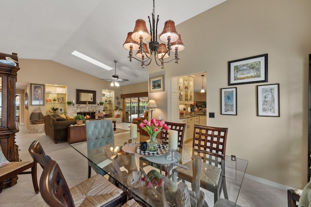 dining area with light tile patterned floors, ceiling fan with notable chandelier, a fireplace, and lofted ceiling with skylight