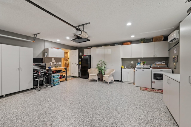 garage with washing machine and dryer, a garage door opener, a wall unit AC, and black fridge