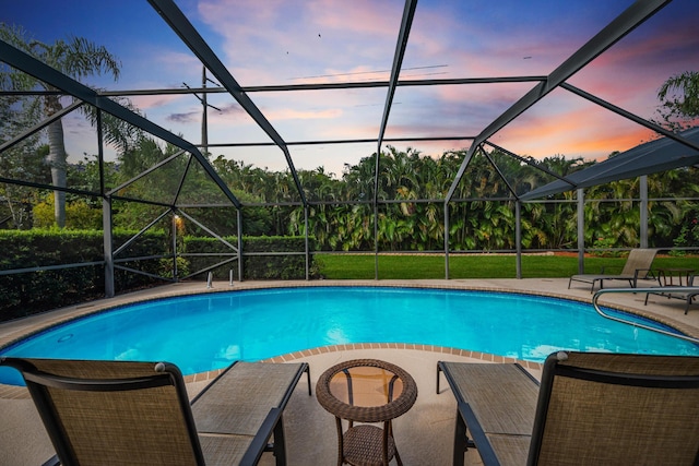 pool at dusk featuring a patio area and glass enclosure