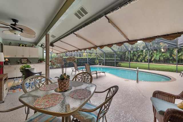 view of pool with glass enclosure, ceiling fan, and a patio