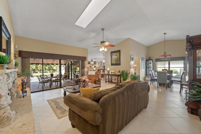 living room featuring ceiling fan with notable chandelier, lofted ceiling with skylight, and light tile patterned flooring