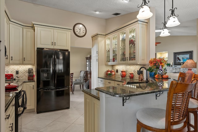 kitchen with cream cabinets, sink, black appliances, and hanging light fixtures