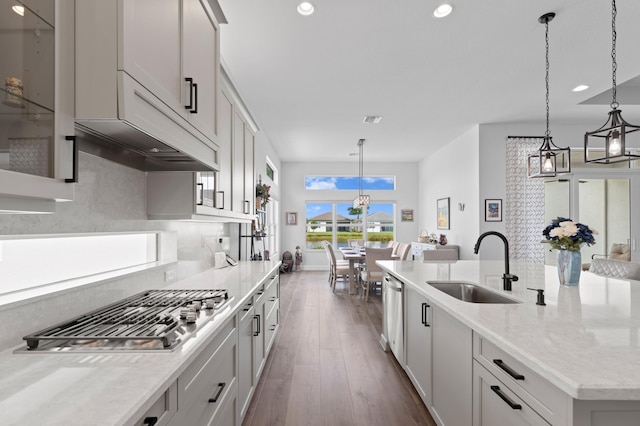 kitchen with decorative light fixtures, sink, a kitchen island with sink, and appliances with stainless steel finishes