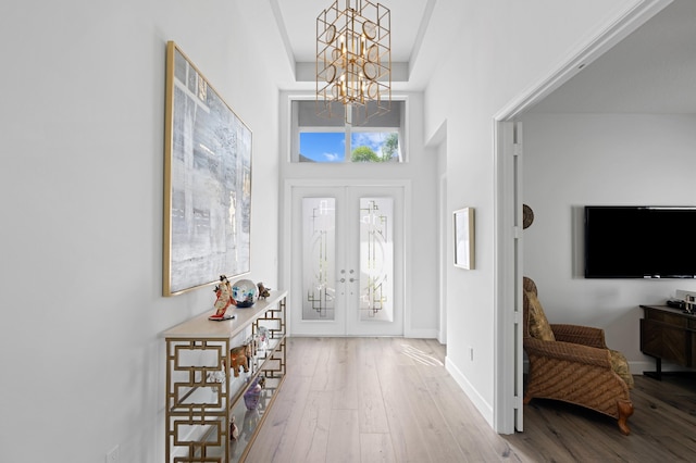 entrance foyer featuring a high ceiling, light hardwood / wood-style flooring, an inviting chandelier, and french doors