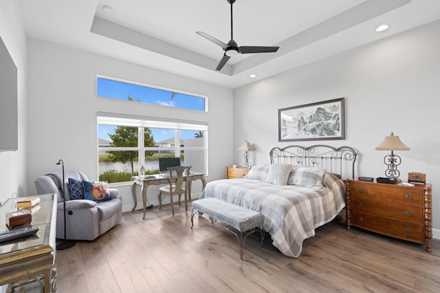 bedroom featuring hardwood / wood-style flooring, ceiling fan, and a tray ceiling