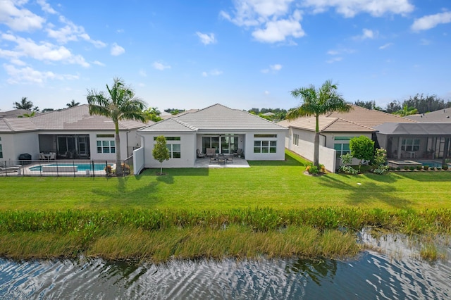 back of property with a lawn, a patio area, and a water view