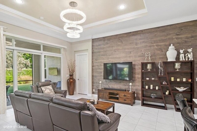 living room featuring wood walls, light tile patterned floors, an inviting chandelier, a raised ceiling, and crown molding