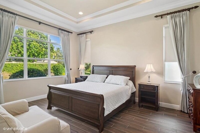 bedroom featuring dark hardwood / wood-style floors, a tray ceiling, and ornamental molding