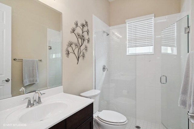 bathroom featuring vanity, toilet, and a shower with shower door