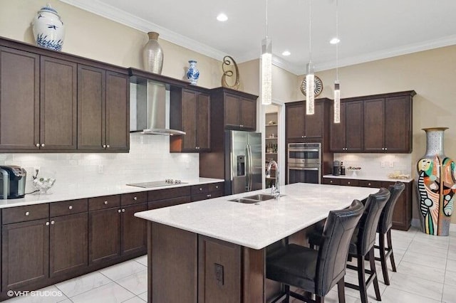 kitchen with a center island with sink, crown molding, stainless steel appliances, sink, and wall chimney exhaust hood