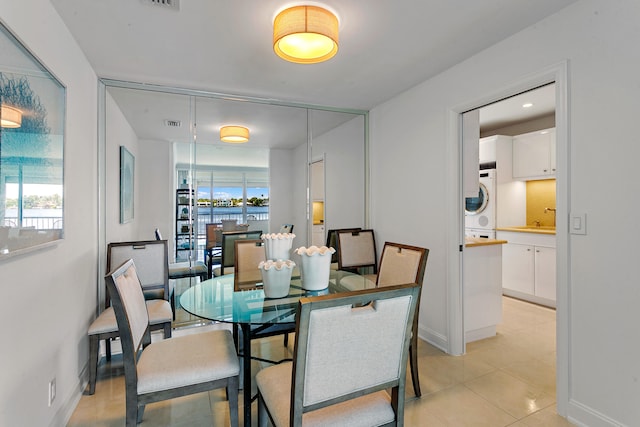 tiled dining space featuring sink and stacked washer / drying machine