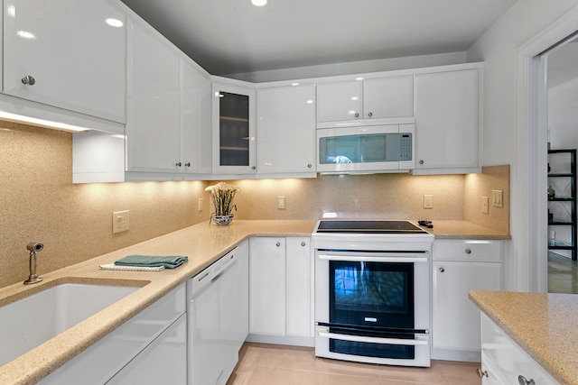 kitchen featuring white appliances, sink, white cabinetry, decorative backsplash, and light tile patterned floors