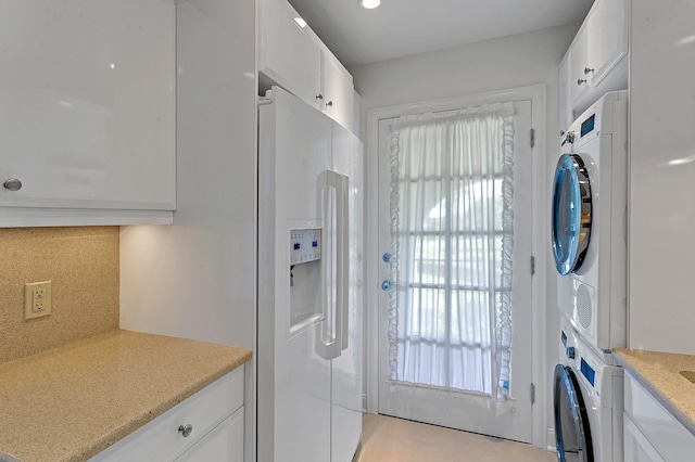 laundry room with stacked washer and dryer and light tile patterned floors