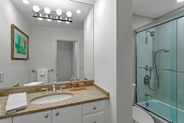 full bathroom featuring vanity, shower / bath combination with glass door, and toilet