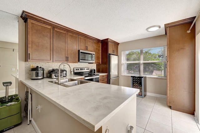 kitchen with a peninsula, appliances with stainless steel finishes, light countertops, and a sink