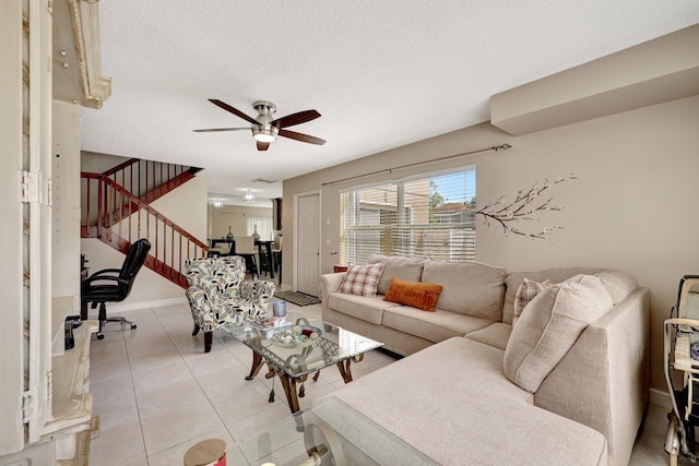 living room with light tile patterned floors, visible vents, ceiling fan, a textured ceiling, and stairs