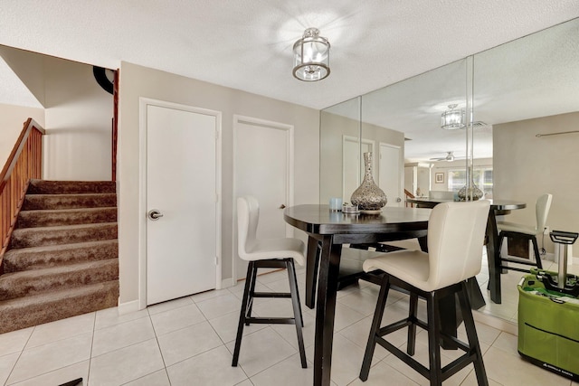 dining space featuring stairs, a textured ceiling, and light tile patterned flooring