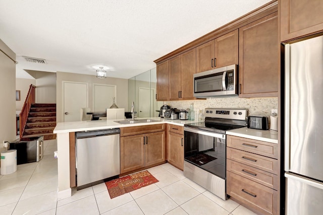 kitchen with light tile patterned floors, light countertops, appliances with stainless steel finishes, and a peninsula