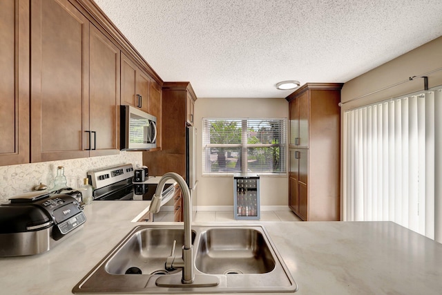 kitchen with brown cabinets, stainless steel appliances, a sink, and light countertops