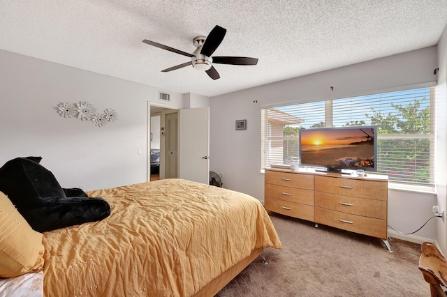 bedroom with a textured ceiling, visible vents, carpet, and a ceiling fan