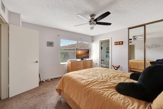 carpeted bedroom with a closet, ceiling fan, a textured ceiling, and ensuite bath