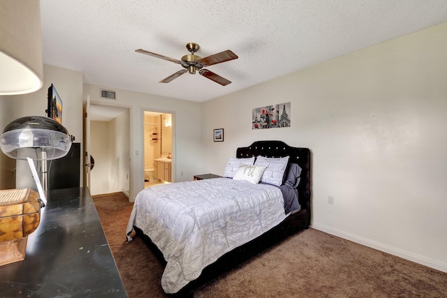 bedroom featuring baseboards, visible vents, ensuite bath, dark colored carpet, and a textured ceiling