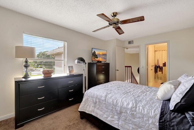 bedroom with a ceiling fan, light colored carpet, visible vents, and a textured ceiling