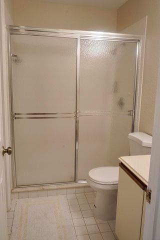 bathroom featuring vanity, a shower with shower door, tile patterned flooring, and toilet