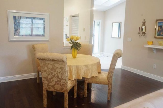 dining room featuring vaulted ceiling with skylight and dark hardwood / wood-style flooring