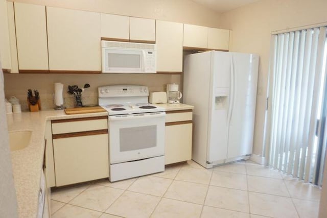 kitchen with white cabinetry, light tile patterned floors, white appliances, and vaulted ceiling