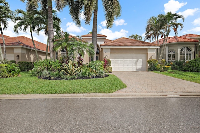 mediterranean / spanish-style home featuring a front lawn and a garage