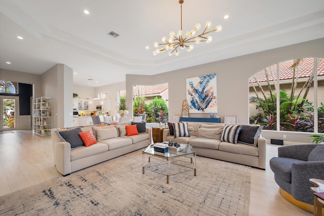 living room with a notable chandelier, light hardwood / wood-style flooring, and plenty of natural light