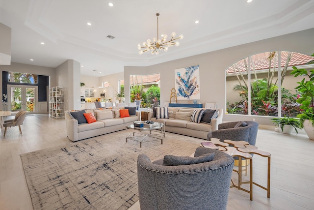 living room featuring a chandelier, light wood-type flooring, and a raised ceiling