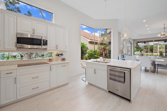 kitchen with white cabinets, stainless steel appliances, sink, and pendant lighting