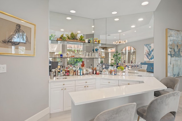 bar featuring white cabinetry, light hardwood / wood-style floors, sink, and pendant lighting