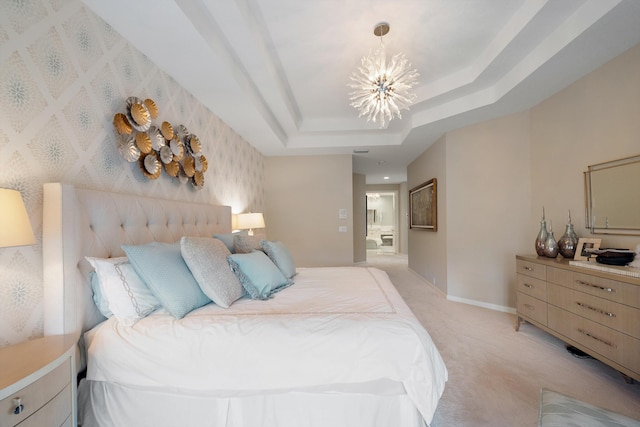 bedroom featuring an inviting chandelier, connected bathroom, light colored carpet, and a tray ceiling