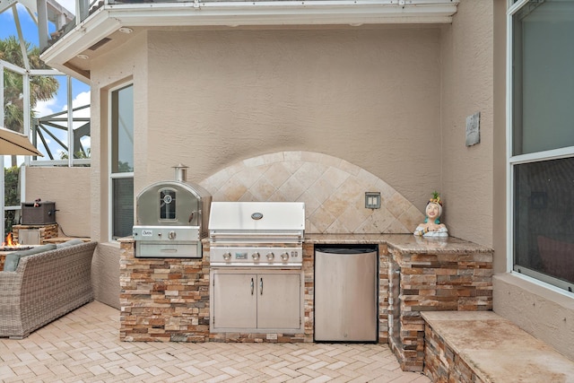 view of patio featuring an outdoor kitchen, a grill, and glass enclosure