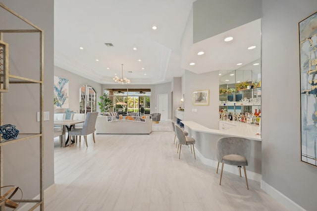 bar featuring white cabinetry, light hardwood / wood-style floors, a chandelier, and hanging light fixtures