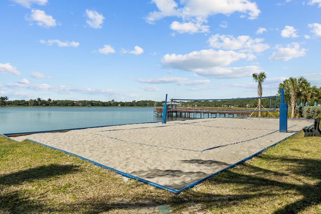 view of community featuring a water view, a lawn, and volleyball court