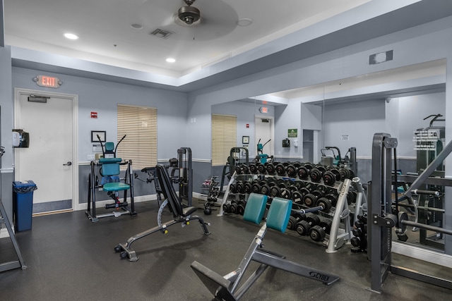 gym with a tray ceiling and ceiling fan