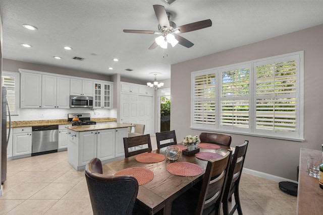 dining area featuring light tile patterned flooring and ceiling fan with notable chandelier