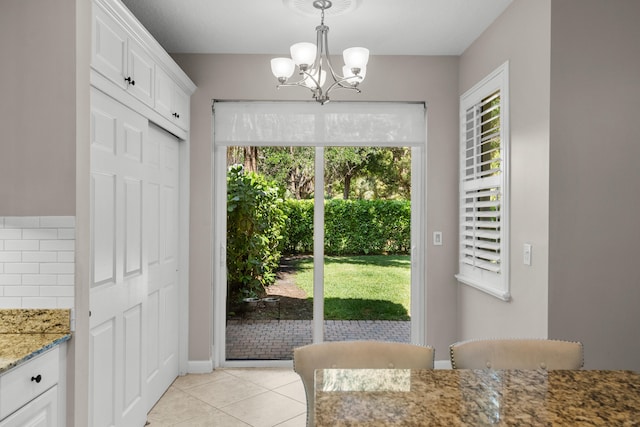 dining area with a wealth of natural light, a notable chandelier, and light tile patterned floors