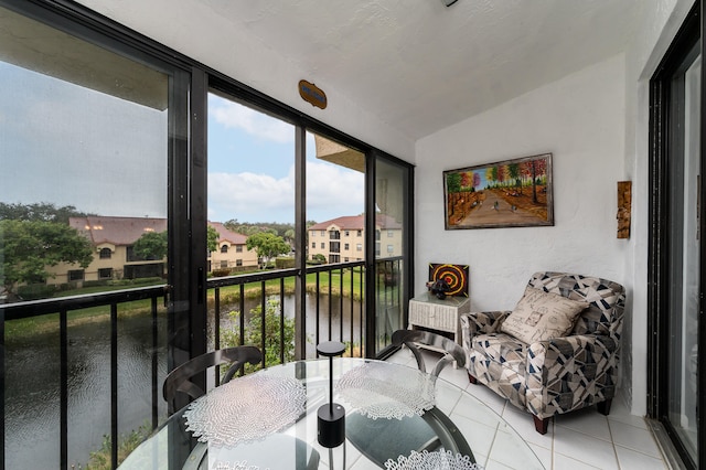 sunroom / solarium featuring lofted ceiling and a water view