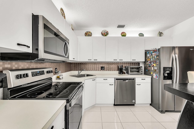 kitchen with sink, a textured ceiling, stainless steel appliances, white cabinets, and decorative backsplash