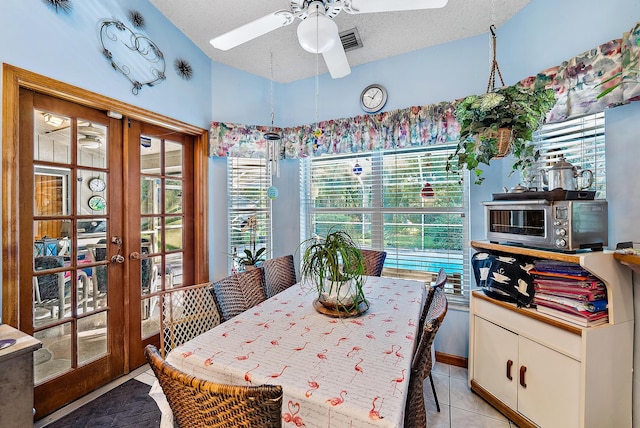 tiled dining room with french doors, a textured ceiling, and ceiling fan