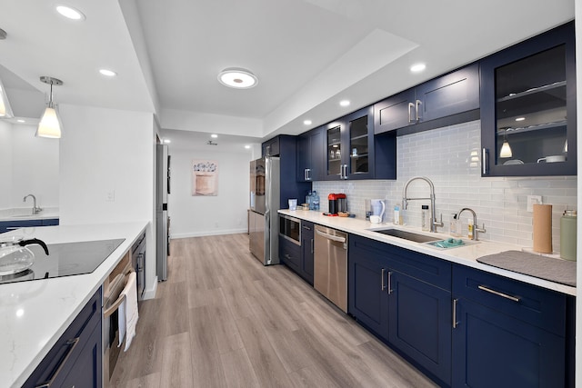 kitchen with blue cabinets, sink, pendant lighting, stainless steel appliances, and light hardwood / wood-style floors