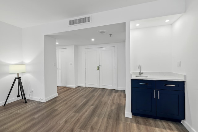 bar featuring blue cabinets, sink, and hardwood / wood-style floors