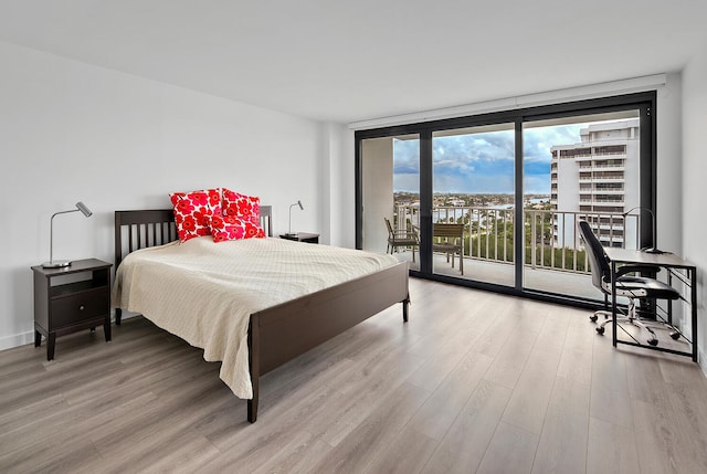 bedroom with expansive windows, access to outside, and light hardwood / wood-style floors