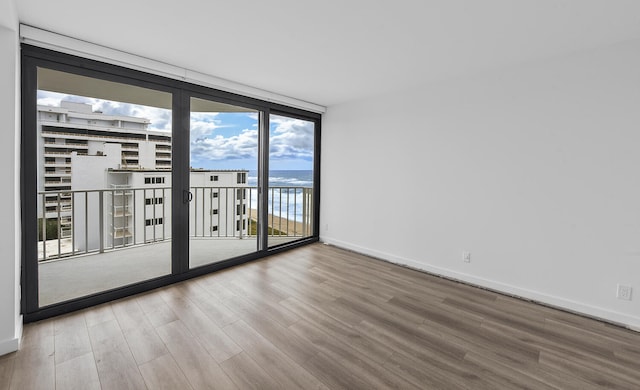 spare room featuring a water view, a wall of windows, and wood-type flooring