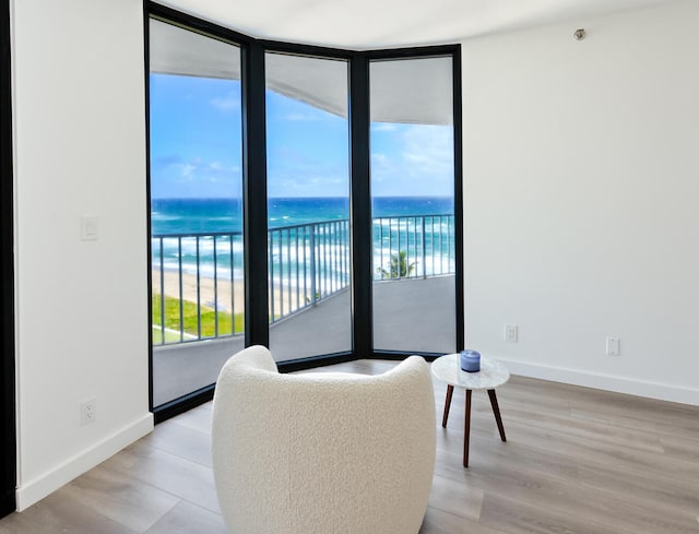 living room with a water view, expansive windows, light hardwood / wood-style flooring, and a wealth of natural light